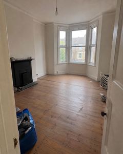 Example phone photo: an empty living room with a bay window, a black fireplace and bags on the floor