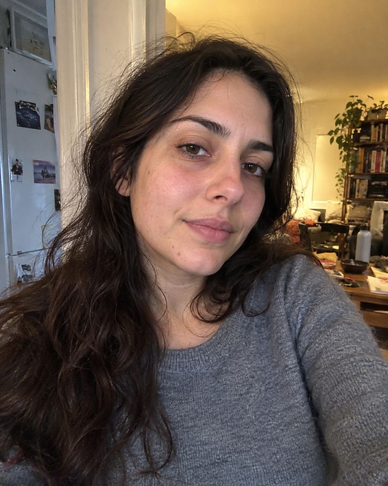 Example phone photo: a selfie of a woman with long dark hair in a grey sweater at home