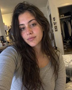 Example phone photo: a selfie of a woman with long dark hair in a grey top in her bedroom