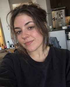 Example phone photo: a selfie of a woman with dark hair in a black sweater in her kitchen