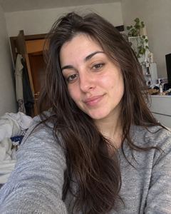 Example phone photo: a selfie of a woman with long dark hair in a grey top at home