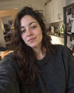 Example phone photo: a selfie of a woman with long dark hair in a grey sweater in her kitchen