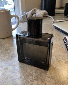 Example phone photo: a dark glass perfume bottle on a kitchen counter beside a laptop